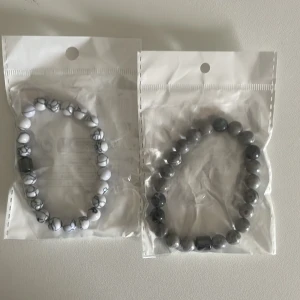 Två armband med pärlor - Två armband med pärlor, ett i grått och ett i vitt med grå marmorering. Båda armbanden har elastiska band för enkel passform. Ett armband för 49 två för 59. Pris går att diskutera 