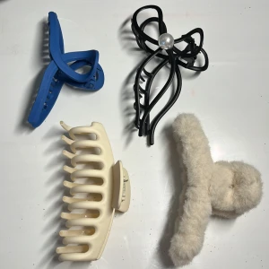 Hårklämmor och håraccessoarer - Fyra olika håraccessoarer: en blå hårklämma, en svart hårklämma med pärldetalj, en beige hårklämma och en vit fluffig håraccessoar. OBS! 19 för varje och 59 för alla fyra!