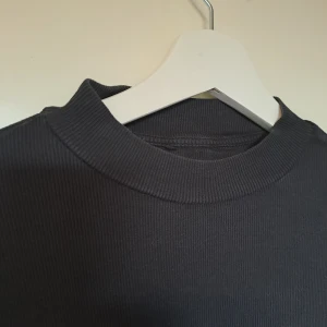 Svart halv-polo  - Säljer denna fina, långärmade topp med halv-polo krage. Den är ribbad och i toppenbra skick! 