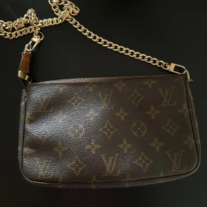 Louis Vuitton pochette - Äkta Louis Vuitton väska, köpt för 6500 vintage. Så fin fortfarande!! Många liknande har lite hackig dragkedja men denna är helt rak när man stänger. Har köpt bandet till själv! 
