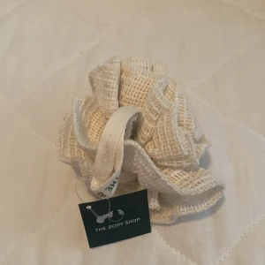 Vit badsvamp från The Body Shop - En vit badsvamp från The Body Shop. Badsvampen är tillverkad av ett nätmaterial och har en praktisk ögla för upphängning.