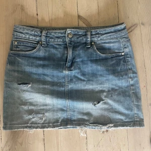 Jeanskjol - Säljer min super snygga vintage lowwaist jeanskjol som har små söndriga detaljer. Super snygg men är tyvärr för liten. Mått tvärsöver midjan/höften (lowwaist) är 38cm, på längden så är kjolen 36cm lång. Skriv om ni har fler frågor! 