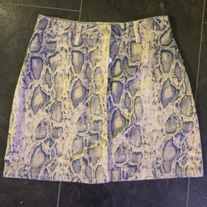 Ormmönstrad kjol från Shein - Säljer en supercool ormmönstrad kjol från Shein i storlek S. Kjolen är kort och har en dragkedja och knappar framtill. Perfekt för en utekväll eller fest! 🐍✨