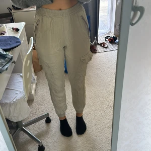 Beige cargopants från BikBok - Säljer ett par snygga beige cargopants från BikBok i storlek XS. Byxorna har en elastisk midja och flera praktiska fickor med dragkedjor och knappar. Perfekta för en avslappnad och trendig look! har även ett par svarta man kan få på köpet om man köper dessa 