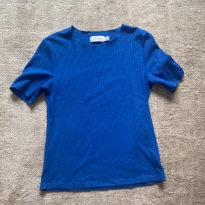 Blå ribbad topp från VILA - Säljer en snygg blå ribbad topp från VILA i storlek XS. Toppen har korta ärmar och en rund halsringning. Perfekt för både vardag och fest! 💙