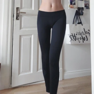 Svarta leggings - Ett par svarta leggings med låg midja. Insidan av midjebandet är limegrön. Leggingsen har en innerficka