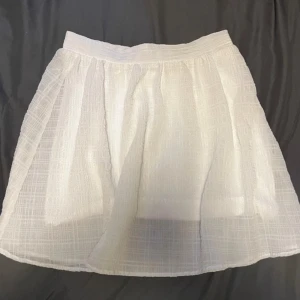 Vit kjol från Divided - Säljer en supersöt vit kjol från Divided. Den är kort och har en luftig och lätt känsla, perfekt för sommaren! Stumt material. Katt finns i hemmet, men allt jag säljer är nytvättat och rollat!✨