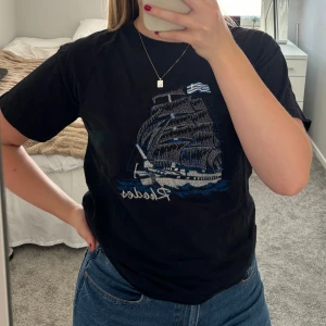 T-shirt med tryck  - En svart T-shirt med broderat tryck från Grekland 🩵. Tröjan är i nyskick och bara provad. Kan mötas upp i Sthlm ⭐️