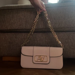 Vit och Guldig handväska. - Vit och Guldig handväska, ena bandet går att ta av men är dock lite smutsigt på ena sidan, använd 1 gång.Original pris 650kr men säljer för 400kr(pris kan diskuteras)