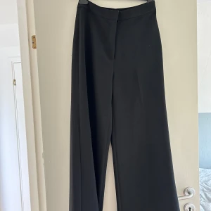 Kostymbyxor  - Svarta kostymbyxor med vida ben och hög midja.  Verkligen så fin modell och material som är i nyskick då de aldrig är använda.  Är i storlek 36 men passar även 38 skulle jag säga 