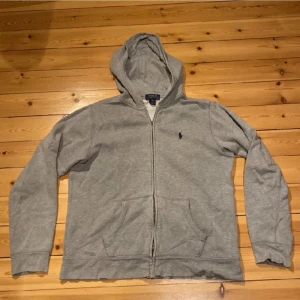 Ralph lauren zip  - Hej jag säljer Ralph Lauren zip i färgen grå för ett bra pris. Skicken är bra förrutom att dragkedjan är sönder men man kan dra upp och ner utan något problem. Vid minsta fråga så är det bara att skriva.