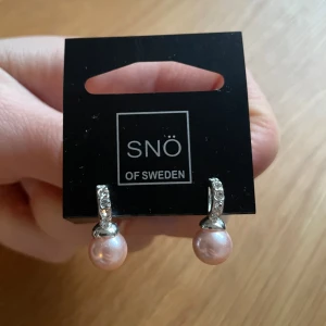 SNÖ örhängen - Oanvända örhängen från SNÖ. Saknar ena fästet på baksidan, se bild.