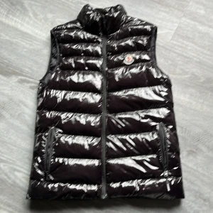 Täckväst moncler - Storlek Medium unisex. Blank svart material. Dragkedja två fickor. Endast provad. 