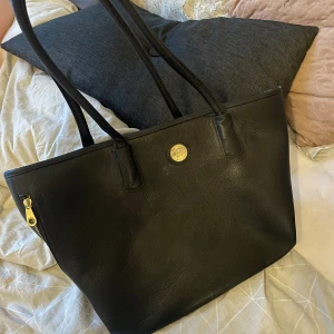 Handväska - Är i bra skick, har däremot små skråmor men inget som syns. Dragkedjor på sidorna. Fler fack. Bredd: ca 42cm Högd: ca 30cm