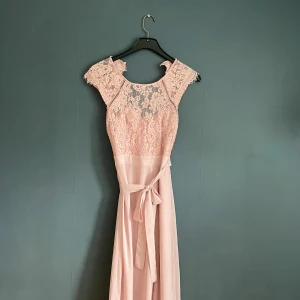 Rosa balklänning - En rosa balklänning med lång passform. Fin öppen rygg och spetsdetaljer på framsidan. Använd sällan.