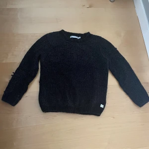 Svart stickad tröja - En svart stickad tröja i strl 150. Tröjan är från lager 157. Några maskor har gått upp men det går lätt att fixa och det syns knappt. Tröjans är len. 