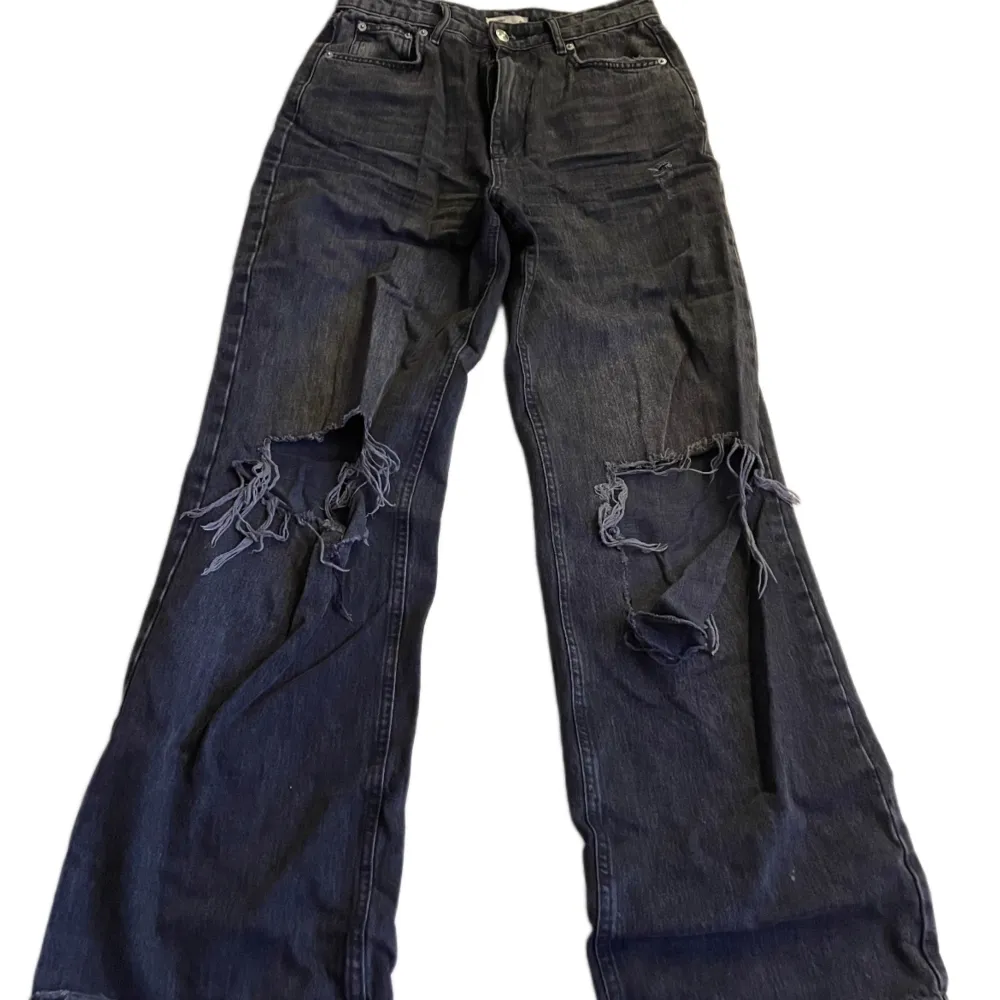 svarta highwaist vida jeans med stora hål! liten fläck bak på låret. strl. 40 från gina tricot! använda, relativt bra skick. Jeans & Byxor.