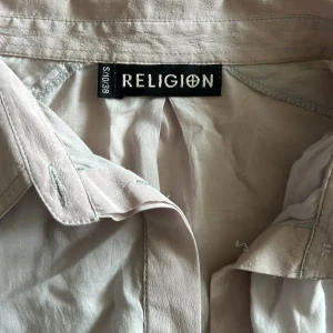 ljuslila religion blus - Jättefin ljuslila blus/ skjorta. Modellen är asymmetrisk och rätt stor. Materialet är lätt och luftigt, bomull och silke. Märket är Religion. Superfin under vår och sommar🪻