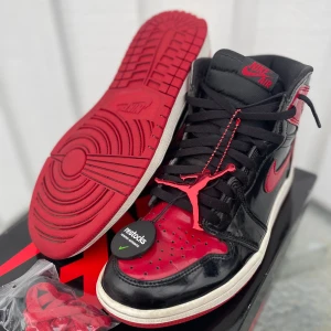 Jordan 1 High Bred Patent - Köpta från restock är i använt skick. Nypris 4000kr. Storlek 44. Extra snören, restock tag kommer med. Väldigt fina och bekväma skor som sticker ut i mängden. Hör av dig om du har några frågor😀