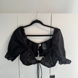 Kort topp - Svart kort topp med knyte mellan brösten  Ny med prislappen kvar! 