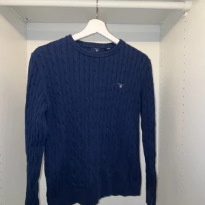GANT Kabelstickad Bomullströja Marinblå - Stickad GANT tröja i marinblått  I bra skick, knappt använd.  Säljer på grund av att jag vuxit ur tröjan  Storlek: 158/164cm  Nypris: 900kr  Har ni frågor eller funderingar är det bara att höra av er! 