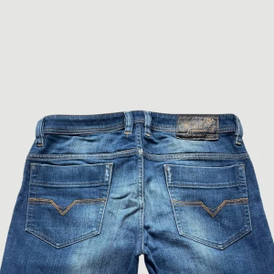 Diesel Raka Jeans Storlek 29 - VARAN KAN KÖPAS DIREKT PÅ VÅR HEMSIDA, ettmarke.se MÄRKE: Diesel Industry. MODELL: Reg Slim-Straight.  FÄRG: Blå. STORLEK: W29 L32. MIDJA RAKT ÖVER: 42 cm. MIDJEHÖJD: 25 cm. TOTALLÄNGD (FRÅN MIDJAN): 110 cm. BENLÄNGD (FRÅN INNELÅRET): 85 cm