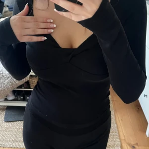 Svart topp - Snygg svart topp med omlott vid brösten. 