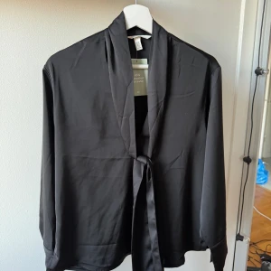 Svart blus med knytband - En svart blus med knytband från H&M aldrig använd med prislapp kvar. 