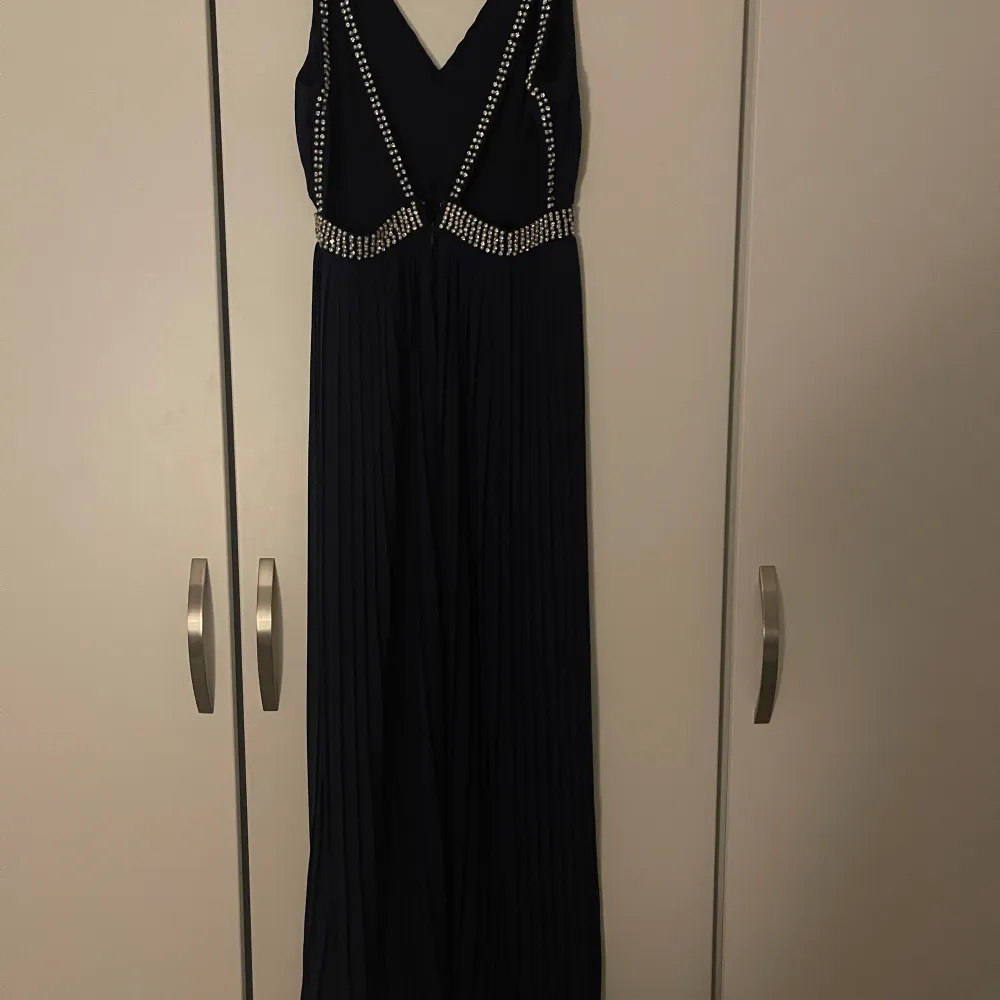Marinblå balklänning i storlek xs/s.  Saknas väldigt få stenar.   Klänningen är använd en gång. Säljer den åt min syster och har därav ingen bild på hur den ser ut på.   Klänningen är från TFNC London.  Är cirka 150-155cm lång.  . Klänningar.