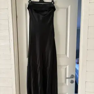 Svart lång satin klänning, aldrig använd lappen kvar. Säljer då den tyvärr är lite lång på mig som är 163 cm. Den har resår på ryggen vilket gör att den sitter uppe ordentligt! Perfekt till bal eller fest😍