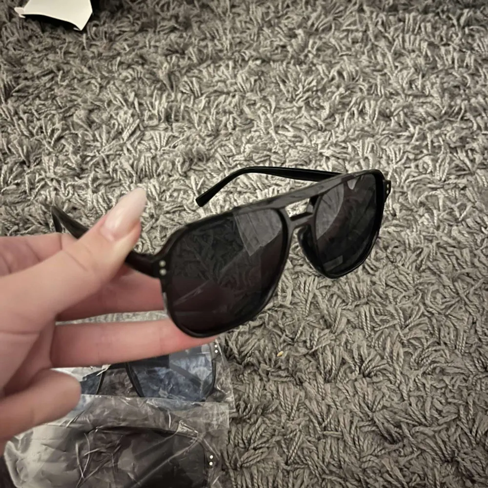 Ett par svarta solglasögon från ensarjoe, helt oanvända och kartong samt tvätt till glaset medföljer. . Accessoarer.