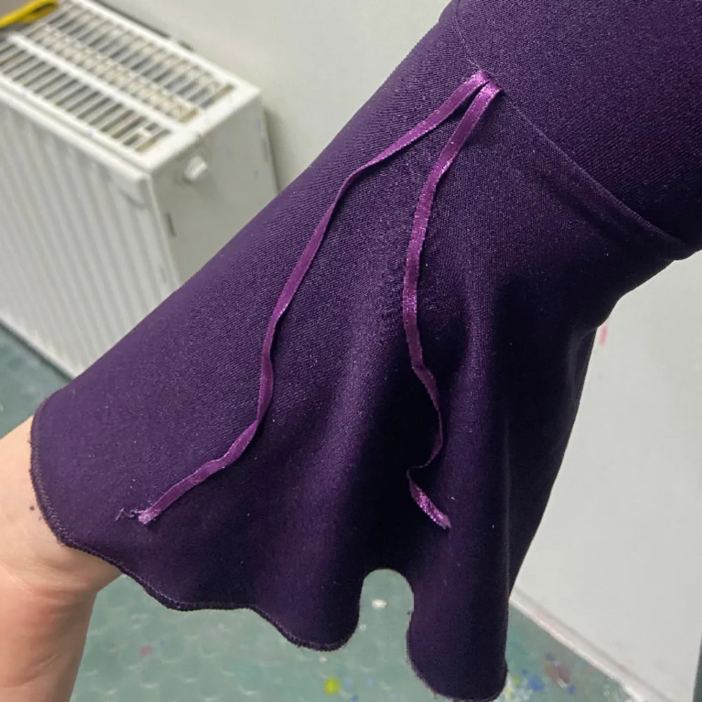 Lila stretchig tröja med flared armar. Luftigt material. På den andra armen finns tyvärr bara ett lila band och inte två som på den andra. Toppar.