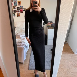 Svart tight klänning  - Superfin svart klänning med rynkade detaljer & slits i bak från na-kd. Helt oanvänd, hann bara inte returnera den i julstressen. Ursprungspris: 499:-. Vid frågor eller funderingar, skriv gärna!