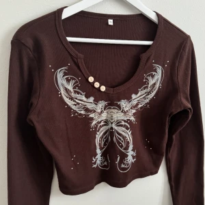 Långärmad topp med rhinestones - Långarmad ribbad topp. Jättefin mönster och har rhinestones. Den är använd men är i bra skick. Inga rhinestones som har gått av