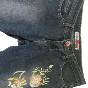 Low waist Bootcut Jeans - Super fina low waist bootcut jeans som tyvärr är för små för mig. Inget fel på byxorna alls utan dom är super snygga med cool blom detalj på låret!🤩 Midja rakt över = 38cm, Ytterben = 104cm, Innerben = 82cm🫶🏻