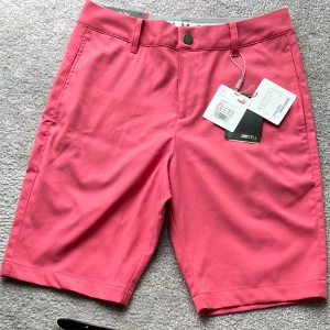 Golfshorts Puma stl 28 rosa - Nya golfshorts Puma stl W28 med lapparna kvar. Obs! Mer matta/gammelrosa än på bilden. Herrmodell.