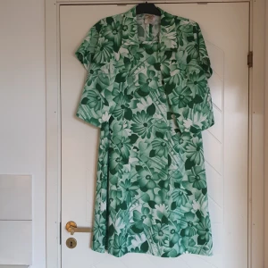 Vintage klänning + kavaj  - Grönblommig vitage klänning och liten kort kavaj jacka. Säljs helst tillsammans. Är nog från 60 talet gissar jag. Skulle gissa på storlek 42/L. Är tvättad med mjukmedel. Luktar ej tant. Från ett djur- och rökfritt hem. 