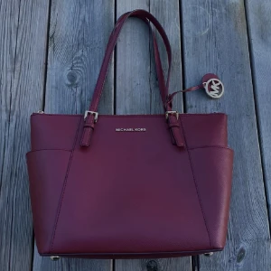 Hand väska - riktigt snygg väska från Micheal Kors! färgen är rödare i verkligheten, typ vinröd. fick i present men har används sparsamt. täcke för väskan ingår. kontakta mig om du vill se fler bilder på väskan ❤️‍🩹