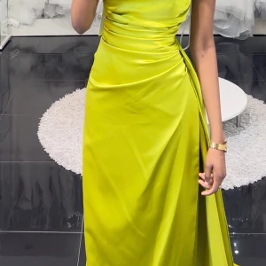 Festklänning  - En vacker klänning i en härlig färg. Klänningen har en elegant design med en djup urringning och en hög slits. Den är perfekt för en festlig tillställning eller en kväll ute.