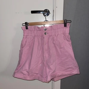 Rosa shorts - Rosa högmidjade söta shorts med två knappar i midjan. Använda ca 1 gång. Storlek 38, normal i storleken.