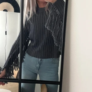 Grå boxig franströja - Mörkgrå stickad tröja från Gina Tricot med fransar på ärmarna, som ny! Använd EN gång. Storlek XS. Passar även en S. 💘 Mått (cm): längd: 54, midjevidd: 114-140, ärmlängd: 61.