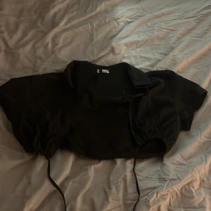 En liten kortärmad kofta - Det är en kort kofta du kan ha över klänningar elr toppar. Den är i helt nytt skick och är ej använd.