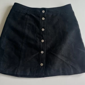 SVART MOCKA KJOL SILVER DETALJER  - Jag säljer en jättesnygg svart kjol i mocca med silvriga detaljer i fram. Kjolen är gammal från H&M och går inte att köpa på deras hemsida. Säljer för att den är för liten på mig och inte kommer till någon användning. Väldigt fint sick!😍