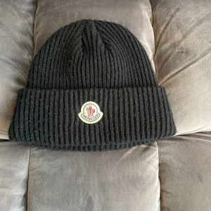 Moncler mössa/svart - Jag säljer min Moncler mössa för att den inte kommer till användning. Den är i fint skick 