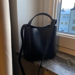 Liten handväska  - Liten handväska i fyrkantig modell från GinaTricot, har ett litet fack med dragkedja inuti. ca 20-25cm hög.  Otroligt fint skick! Endast använd några få gånger.  Ord. pris 299kr