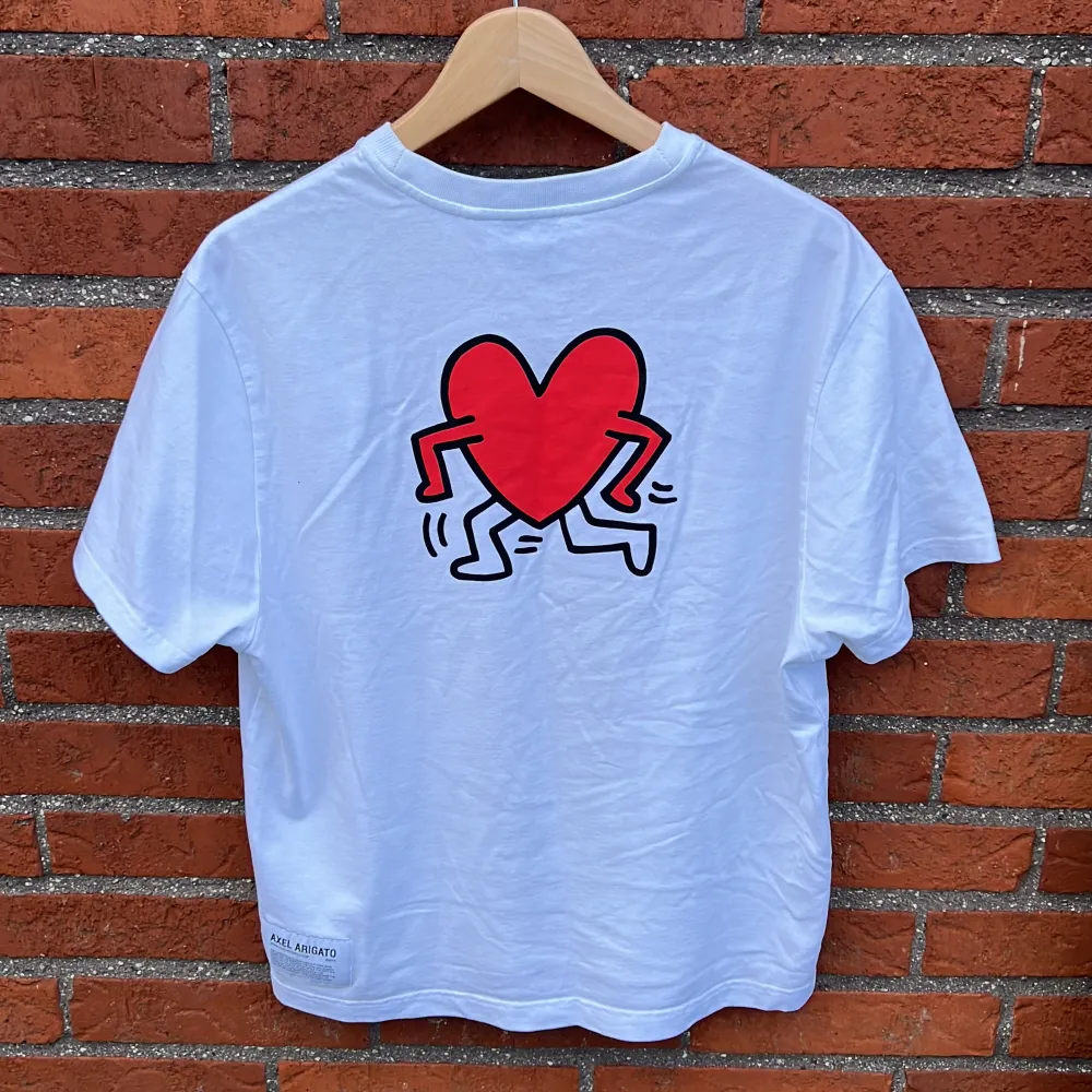 Skitsnygg designer t-shirt av Keith Haring & Axel Arigato, perfekt inför sommaren! Sparsamt använd o i bästa skick. Nypris ca. 900kr !(Kan kombineras i ”paket” med samma modell i svart)!. T-shirts.