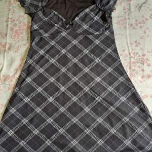 En svart/grå miniklänning med en svart rosett. Köptes från H&M. Den passar S och M.