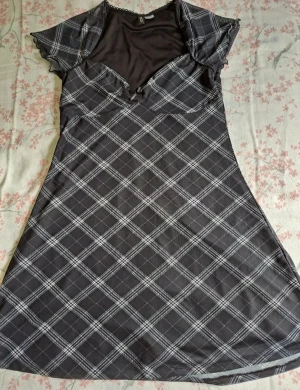 Miniklänning - En svart/grå miniklänning med en svart rosett. Köptes från H&M. Den passar S och M.
