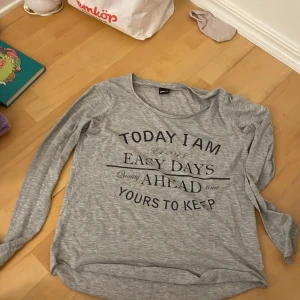 Långärmad tröja  - En grå långärmad tröja. Bra som mjukiströja, men även som underställ. Innehåller text. 