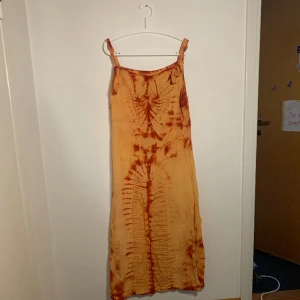 Klänning med batik - Klänning med röd och orange batik med två fickor fram. Från coline diffusion. Står inte  storlek men tror M/L.